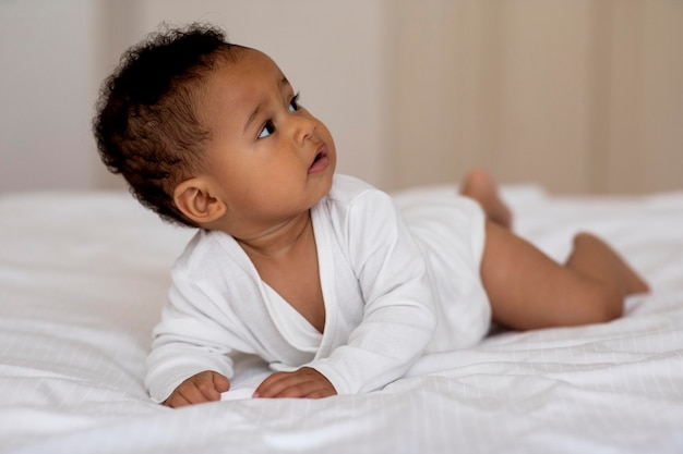 Little Cute Black Baby Boy Lying On His Tummy On Bed Closeup