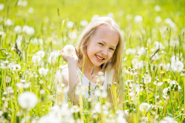 Photo little cute blonde girl with dandelion in white meadow