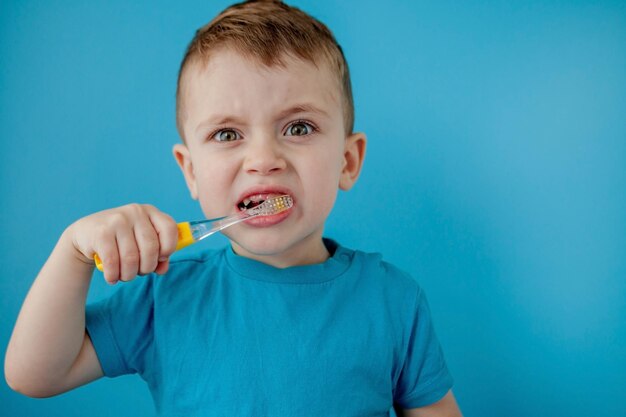 Little cute boy brushing his teeth on blue background