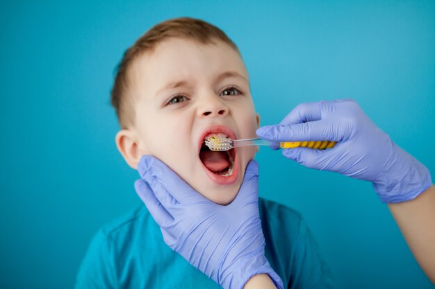 Little cute boy brushing his teeth on blue wall