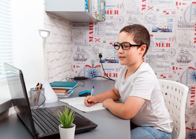 Little cute boy doing online classes at home