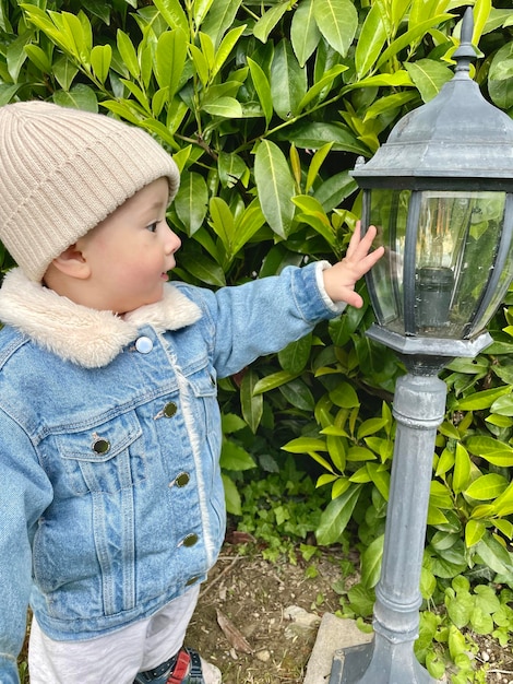Милый мальчик в саду рядом с садовым фонарем