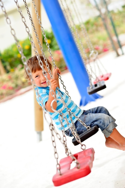 Little cute boy having fun on chain swings.