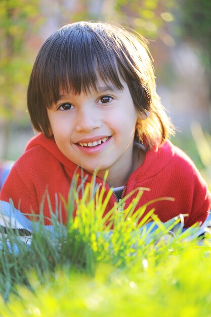 Little cute boy laying on morning summer grass with natural beautiful light