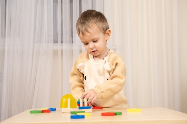Фото Маленький милый мальчик играет с игрушками, сидя за столом.