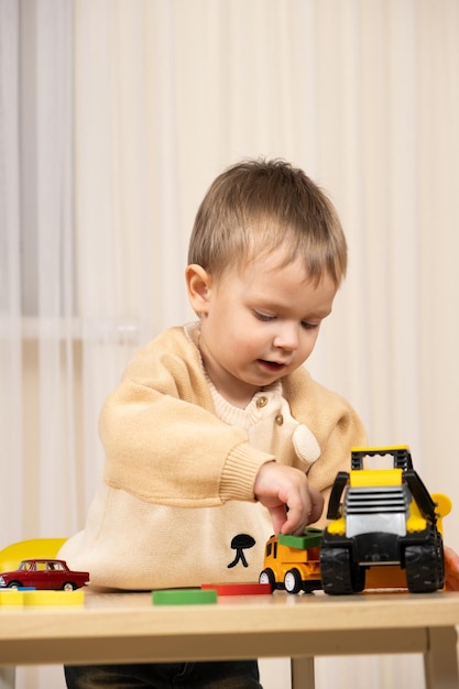 Little cute boy playing with toys while sitting at table