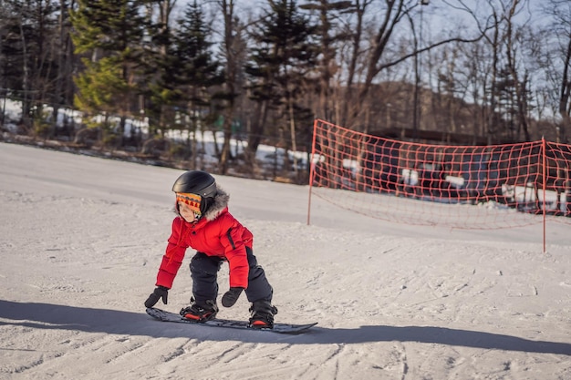 Little cute boy snowboarding Activities for children in winter Children's winter sport Lifestyle