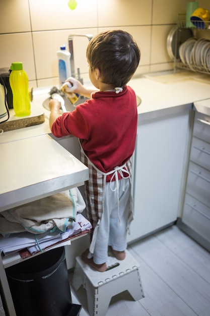 A little cute boy washing dishes