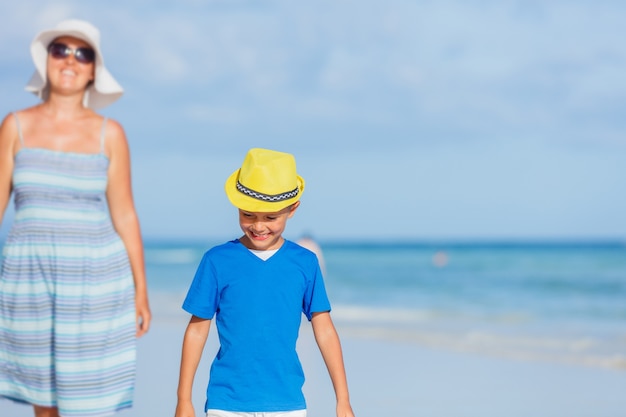 Little cute boy with his mother having fun at the white sand beach