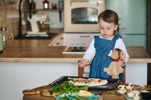 小さなかわいい子供がキッチンでピザを調理する幸せな家族の概念