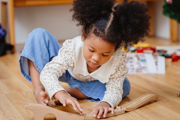 Little cute child girl enjoy playing wood puzzle on the wooden floor at home in living room.