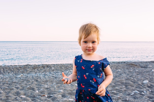 Little cute child girl playing on the seashore in summer