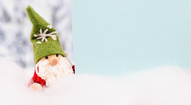 Little cute christmas gnome standing in the snow, forest, festive greeting card, copy space, winter