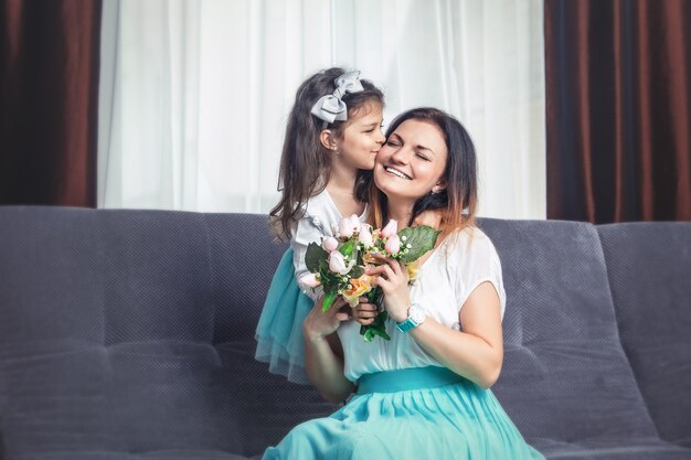 Little cute daughter gives flowers to mom on mother's day at home