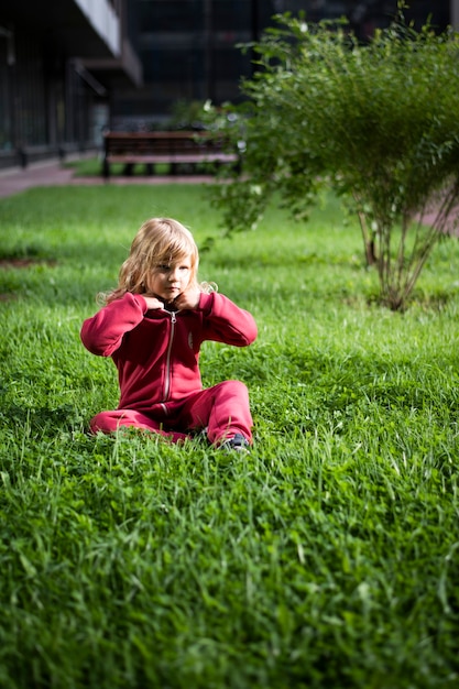 풀밭에 빨간 옷을 입은 5세 금발의 귀여운 소녀