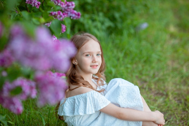 Little cute girl in a blooming lilac in spring