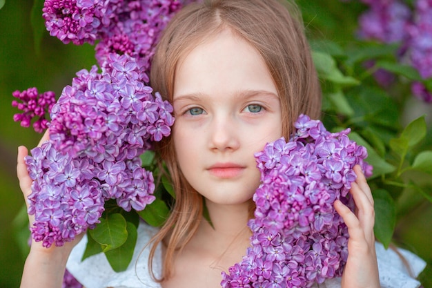 Little cute girl in a blooming lilac in spring