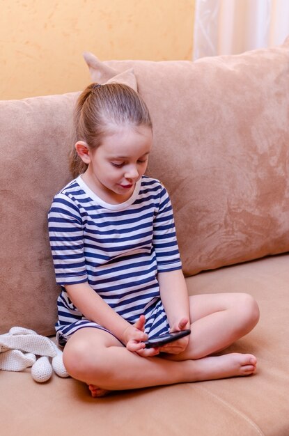 Little cute girl does selfie on smartphone at home