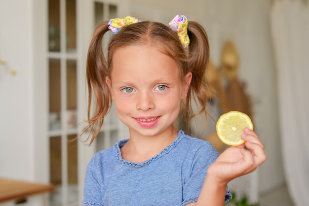 little cute girl drinking tea in the kitchen with lemon