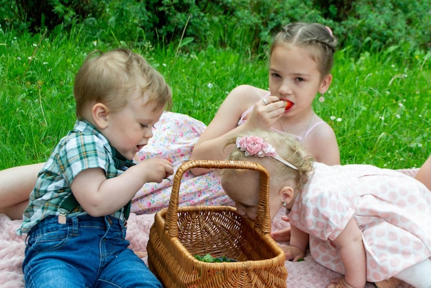 야외에서 바구니에서 딸기를 먹는 귀여운 작은 소녀.