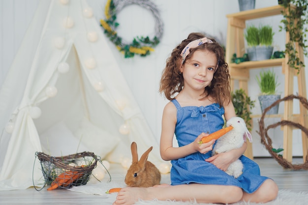 Little cute girl feeding rabbit with carrots