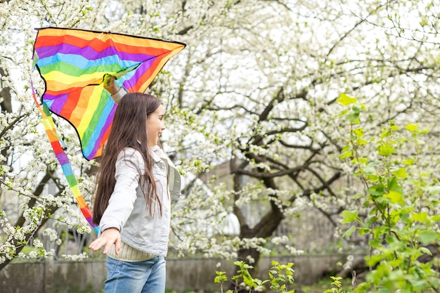 little cute girl flying a rainbow kite.