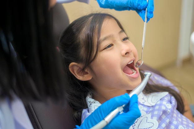 A little cute girl having teeth examined by dentist in dental clinic