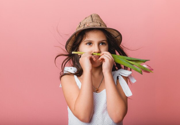 Little cute girl holding a bouquet of tulips on a pink background Happy womens day Place for text Vivid emotions March 8