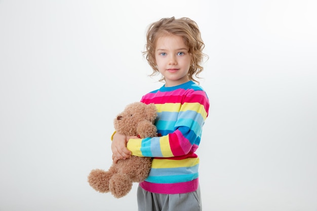 A little cute girl holding a teddy bear isolated on a white background