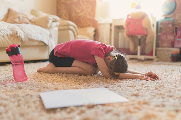 La bambina carina sta praticando ginnastica a casa