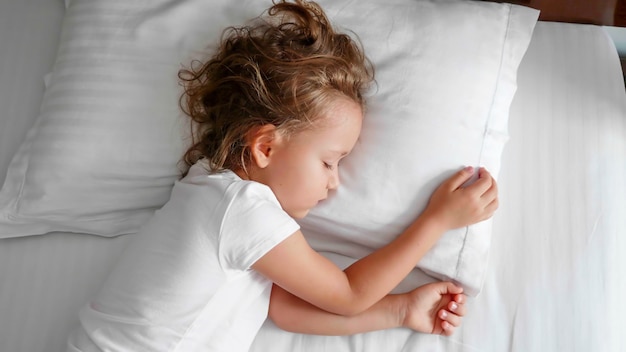 Photo little cute girl is sleeping in bed in the morning