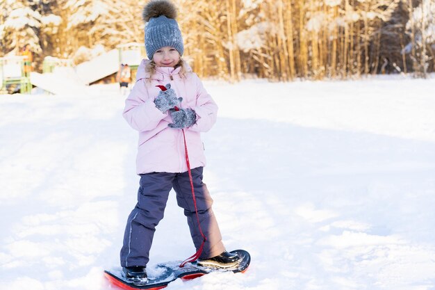 Little cute girl learning to ride a childrens snowboard winter sports for the child safety of active