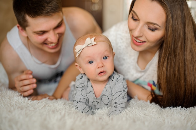 Photo little cute girl lying on the bed among her parents