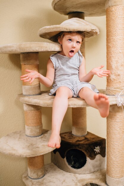 Little cute girl making faces at sore cat house