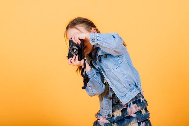 黄色の背景に写真を作る小さなかわいい女の子。