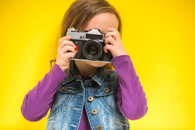 Una piccola ragazza sveglia che fa foto sul giallo