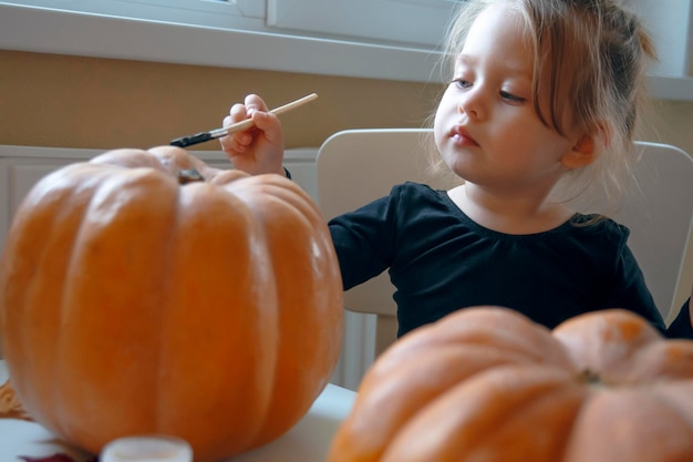 Little cute girl paints the pumpkin Close up Children decorate the house for holiday