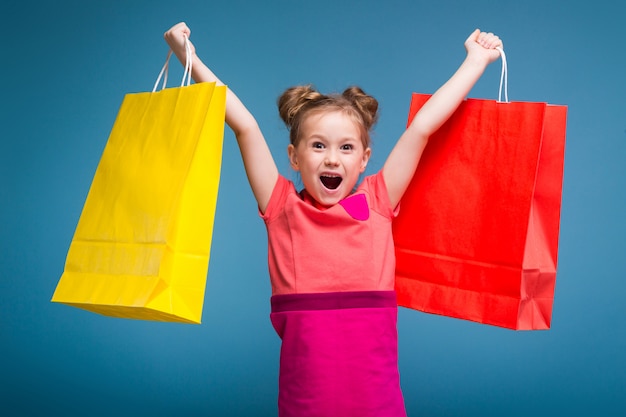 little cute girl in pink dress holds purple paper bag