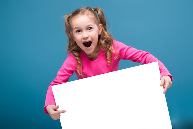 little cute girl in pink shirt with monkey and blue trousers hold empty blank placard