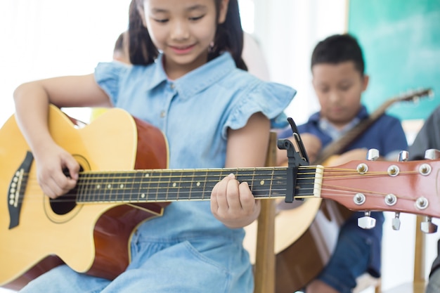 写真 ギターを弾き、音楽教室で笑っているかわいい女の子。