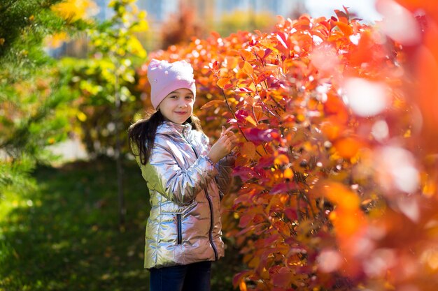 실버 재킷에 작은 귀여운 소녀는 화창한 날에 가을 공원에서 산책
