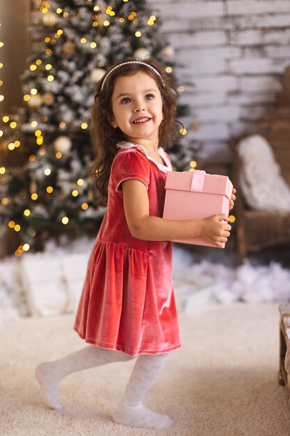 Little cute girl smiling and holding pink present box