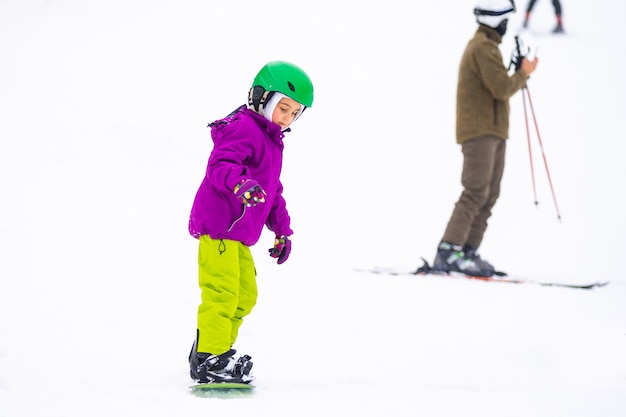 Little Cute Girl Snowboarden in skigebied in zonnige winterdag.