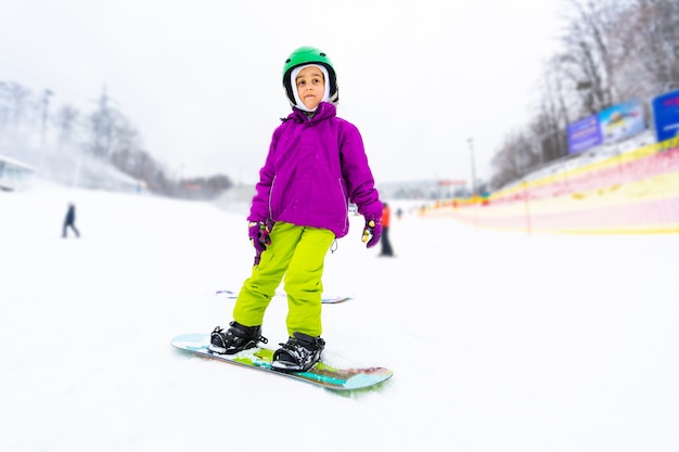 Little Cute Girl Snowboarden in skigebied in zonnige winterdag.