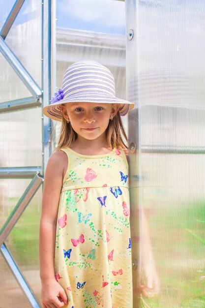 Little cute girl standing in a greenhouse at the garden of her house