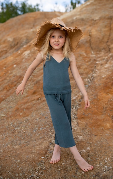 Bambina carina in vestiti alla moda in uno scenario naturale