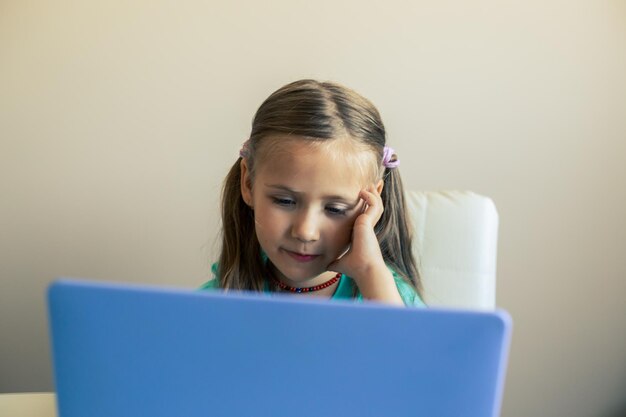 귀여운 소녀는 노트북을 사용하여 화상 통화를 합니다.