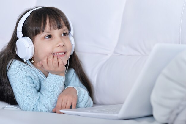 Bambina carina che usa il computer in cuffia