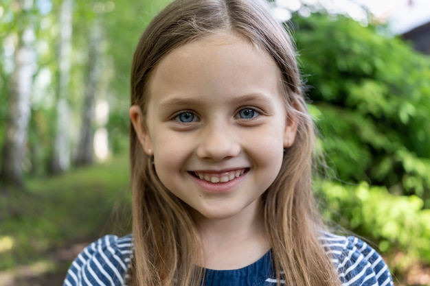 の森で休暇を撮影するカメラのクローズアップでブロンドの髪の小さなかわいい女の子が微笑む