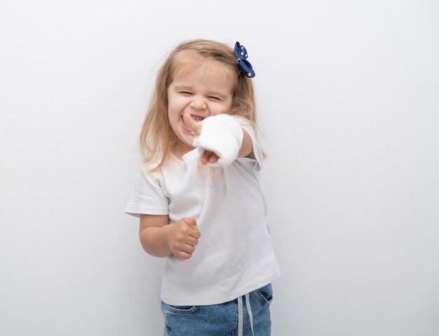 Piccola ragazza carina con la mano in gesso che mostra la classe su sfondo bianco.